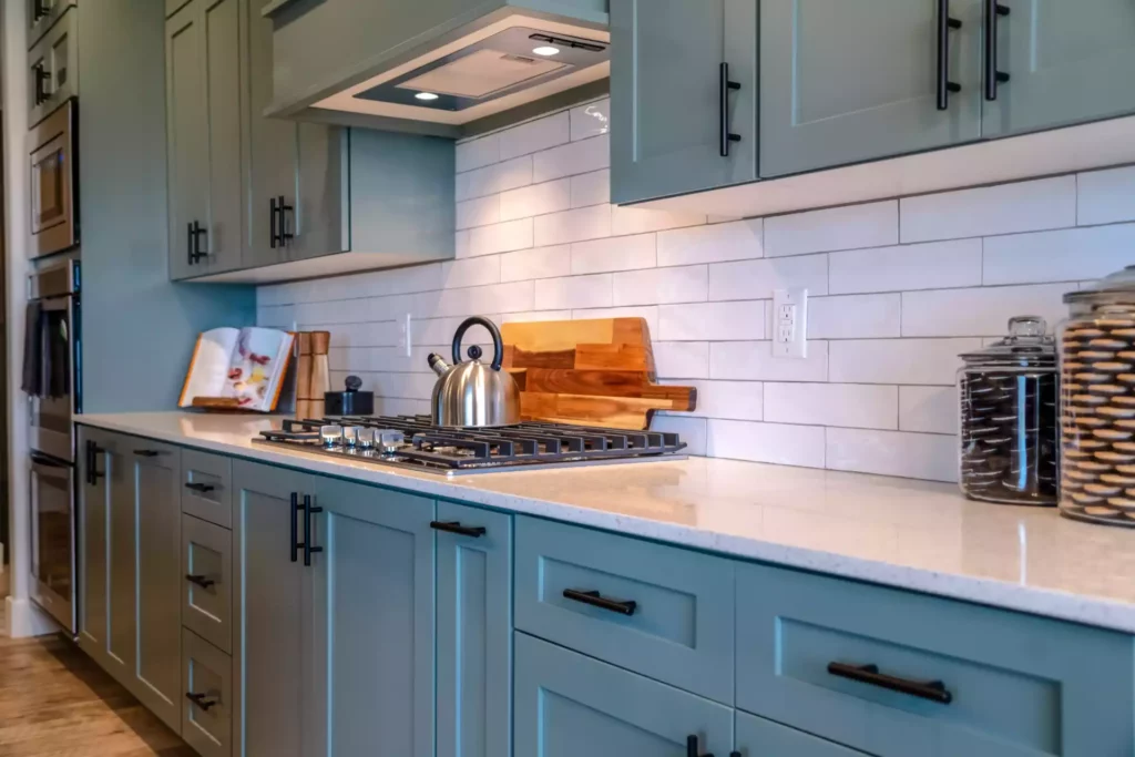 A kitchen with a white tile black splash and blue cabinets.