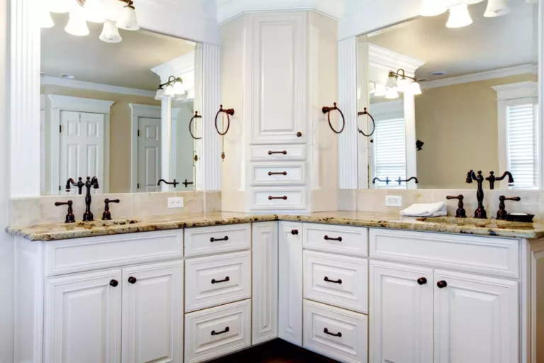 White bathroom cabinets and sinks positioned in the corner.